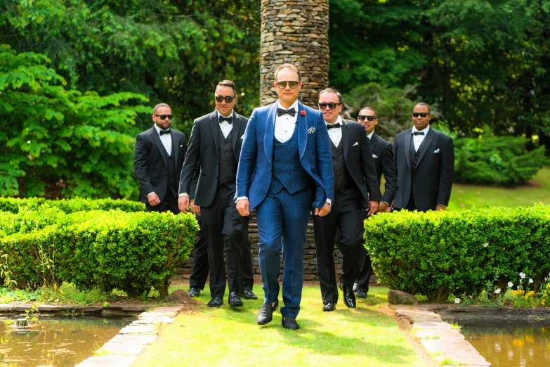 two men in formal wear with a group of people in the background