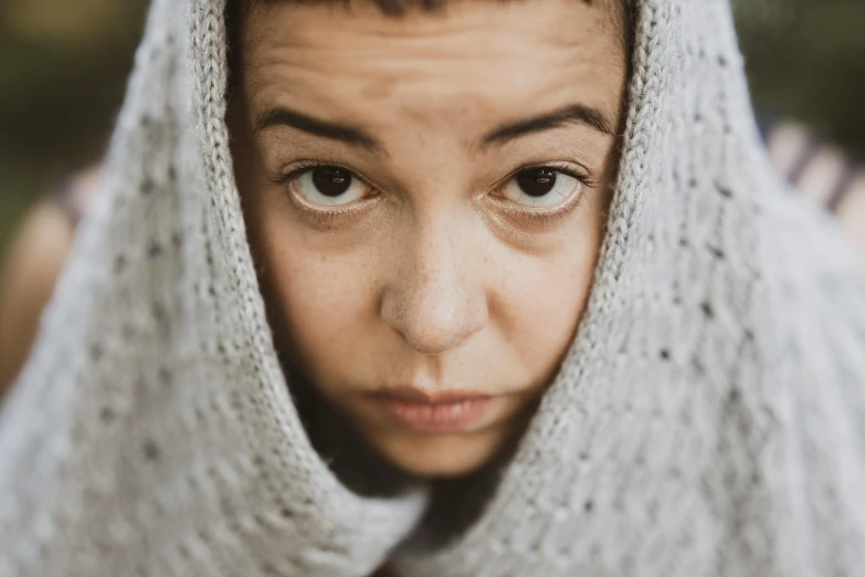 a  wearing a grey hood with her head tucked up