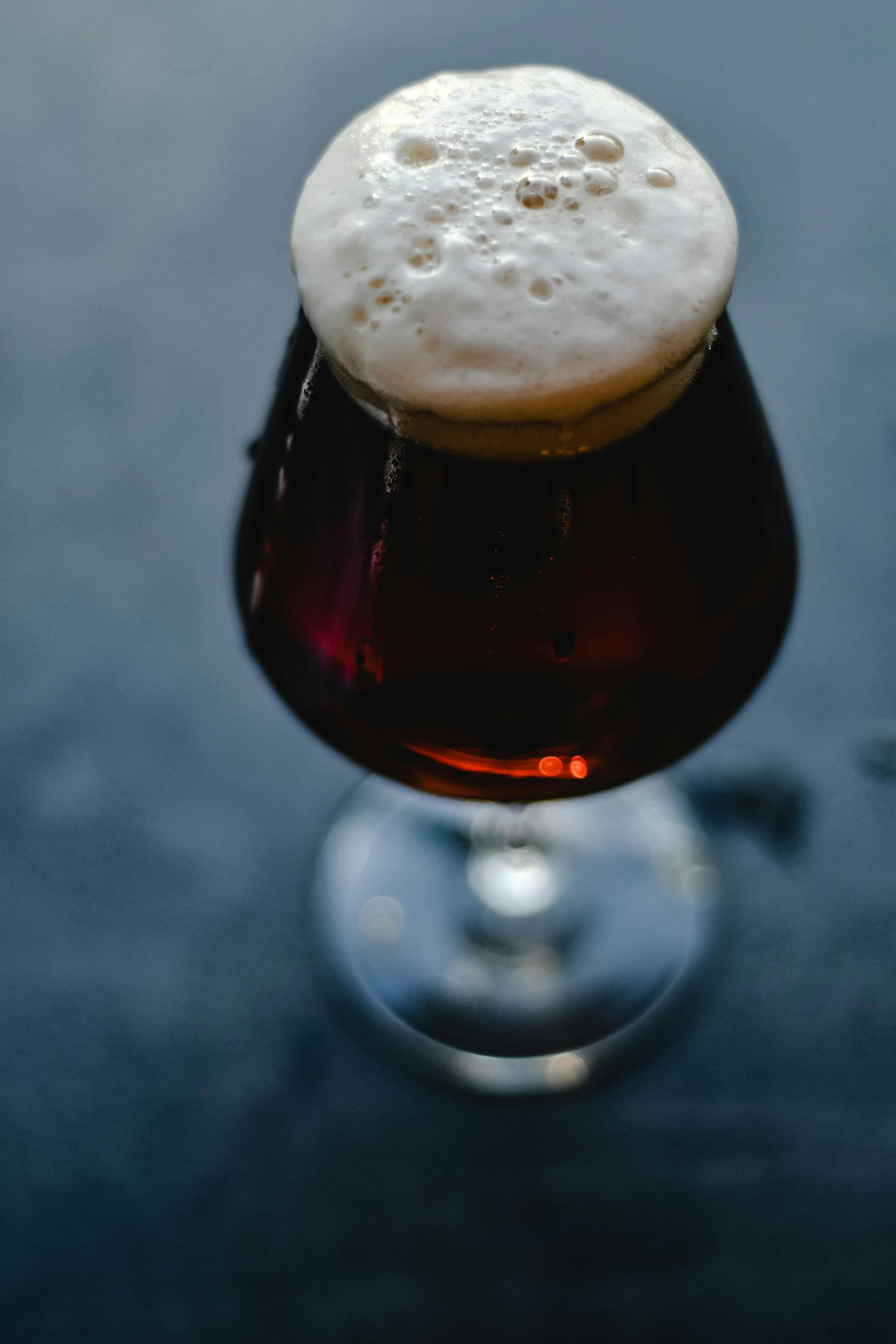 a glass filled with a light beer sitting on a table