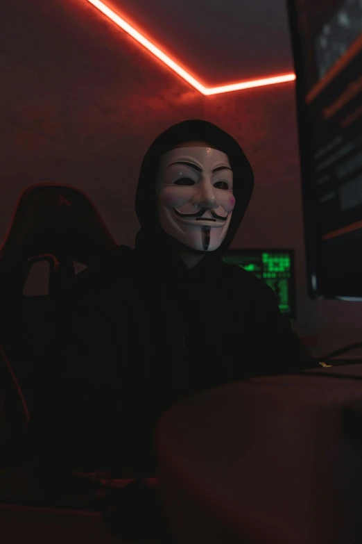 a man sitting at a computer wearing a mask