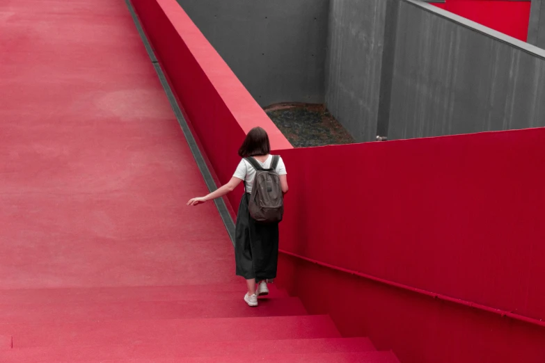 woman walking up a red - painted wall with a book case