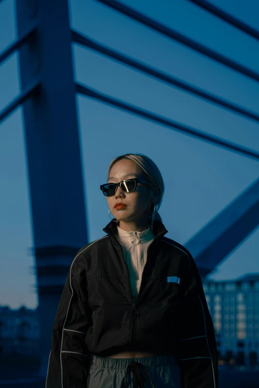 a woman in a black jacket and sunglasses on a city street