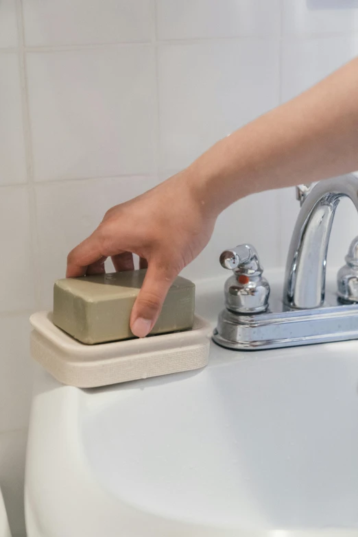 a person's hand is pressing the faucet on the sink