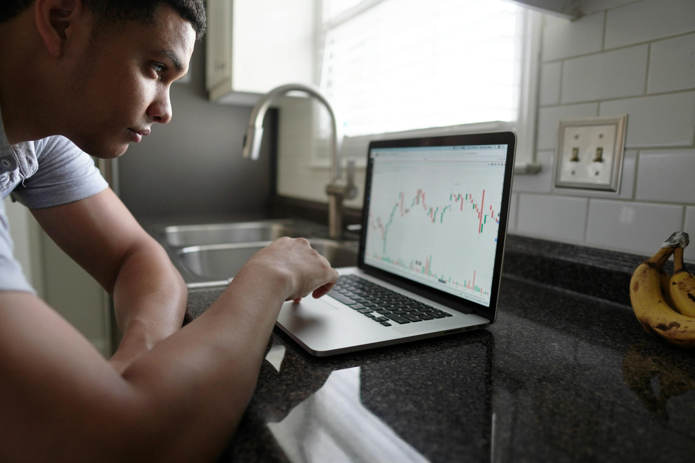 a man is sitting in front of his laptop looking at graphs