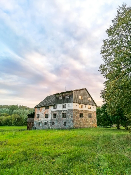 an old house that is in the middle of a grassy field