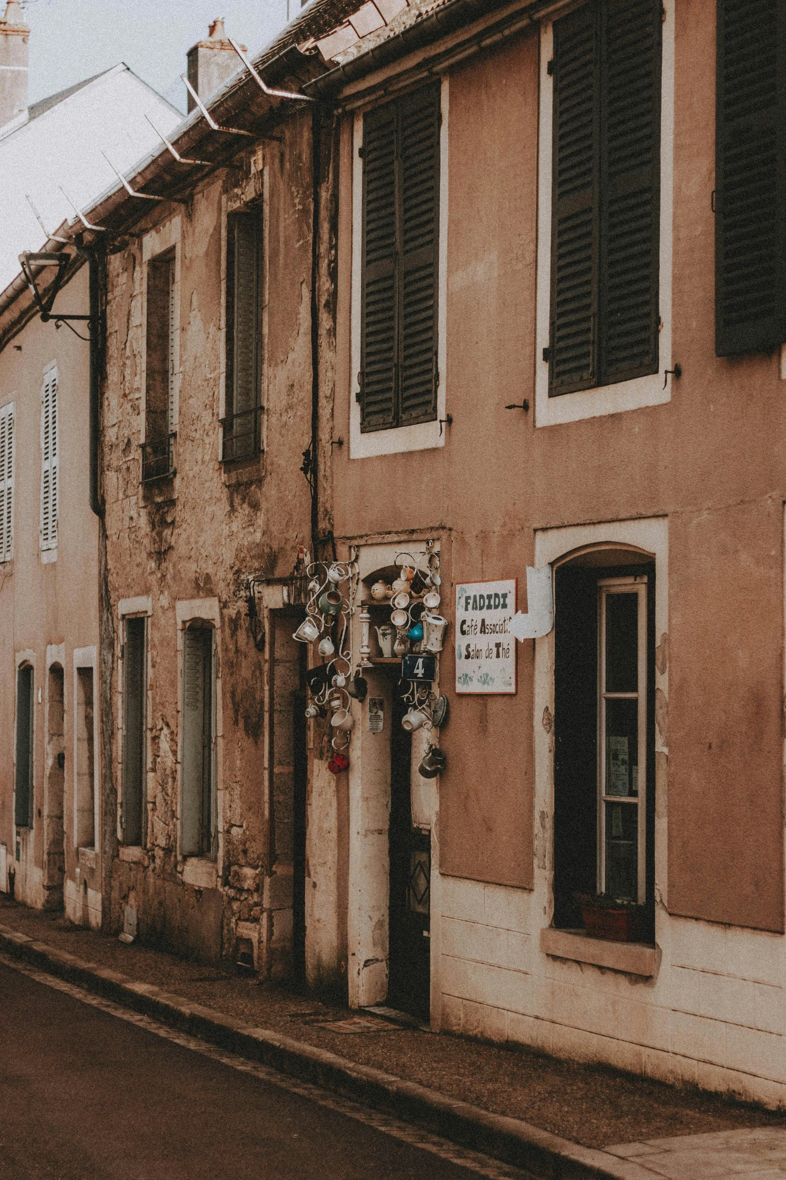 several windows with closed shutters are on a side street