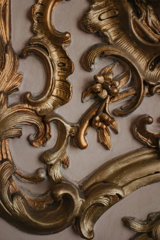 a gold ornate wall decoration with an ornate plant design