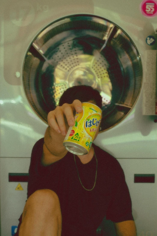 man in black shirt and maroon tshirt holding a can of food up to his face