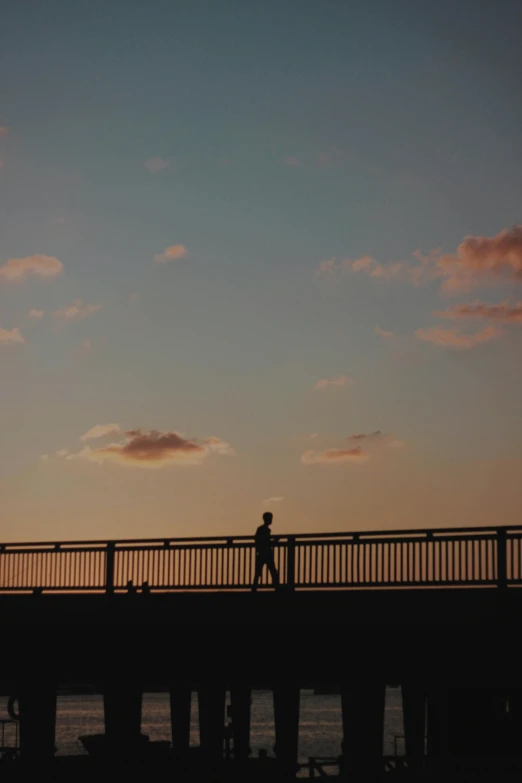 people walking over a bridge near the ocean