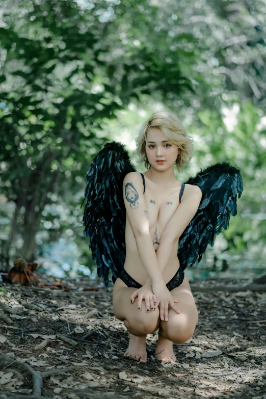 a girl in the woods with an angel outfit and tattoo