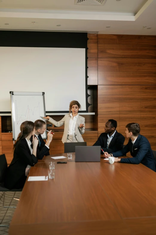 a woman in a business suit giving a presentation at a conference table