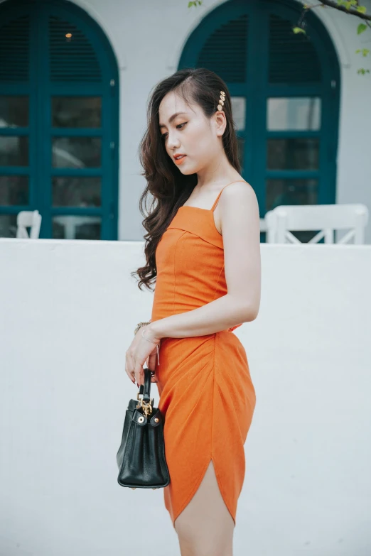 a girl standing in front of a wall holding onto her purse