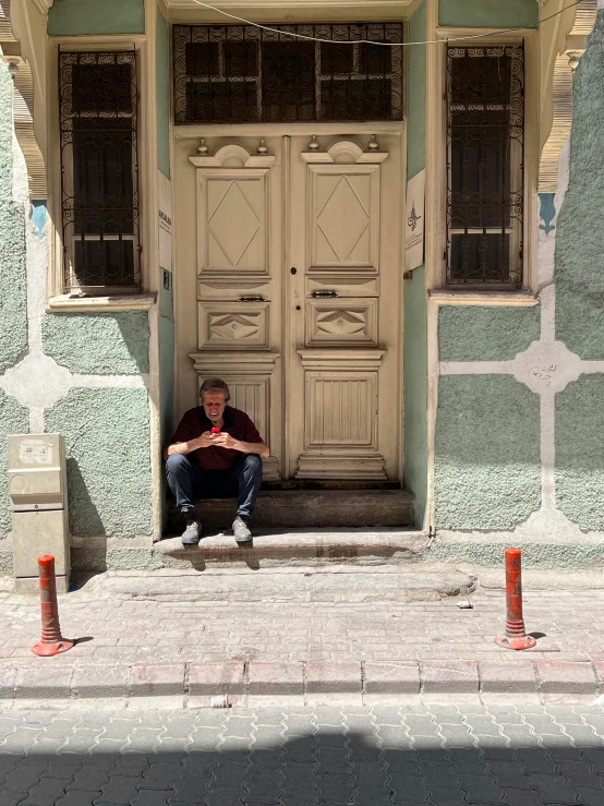 the man is sitting outside of a large door