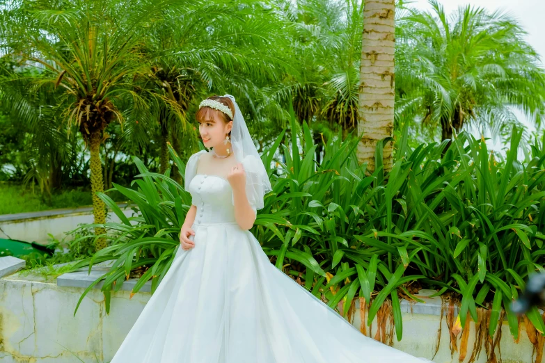 a lady in her bridals in front of palm trees and flowers