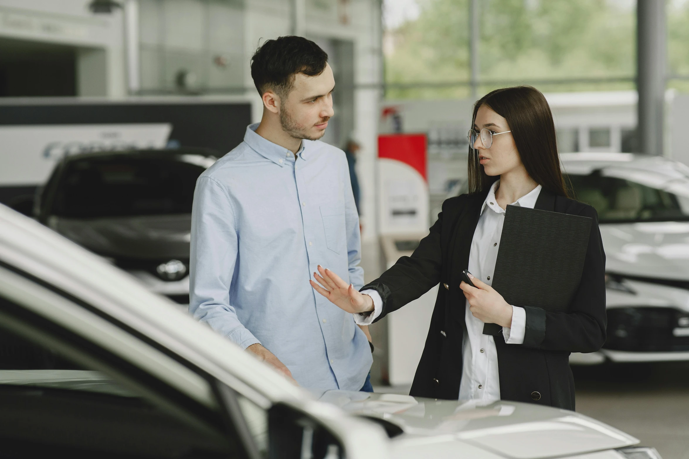 man and woman are looking at the cars on display