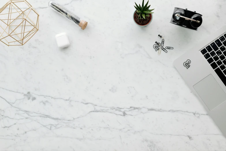 laptop, pen and small plant on a marble desk