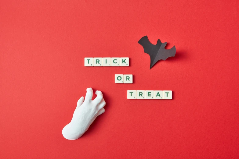 the word trick or treat spelled with scrabbles on red paper