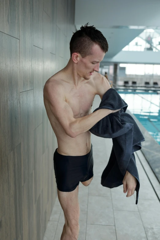 a man is walking into a swimming pool with his towel