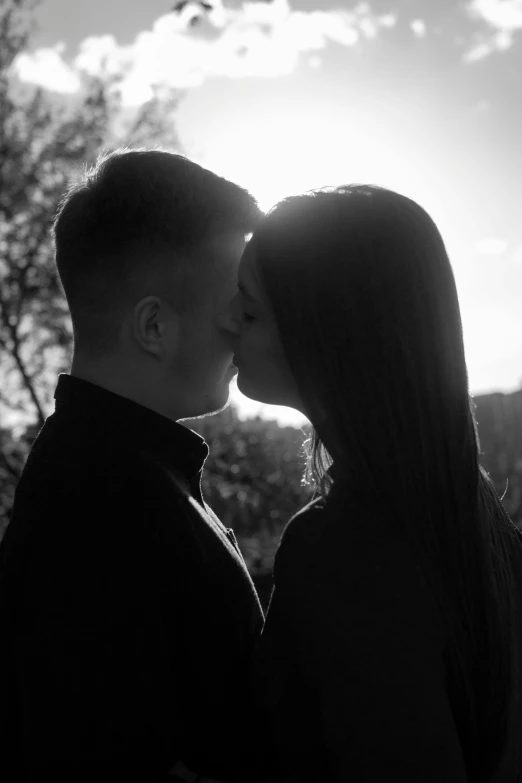 a young couple kissing in front of the sun