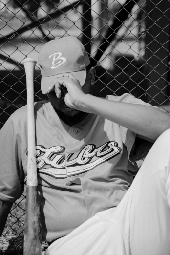 a baseball player resting in the dugout of a fence