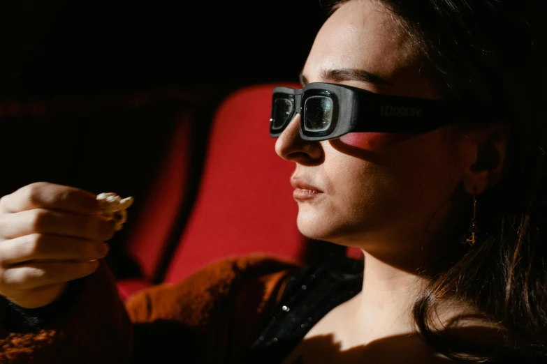 a girl is in a dark room, wearing black glasses