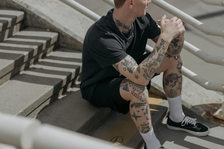a person with tattoos sitting on the stairs of stairs