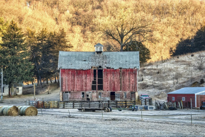 a red barn sitting next to a hill on top of a field