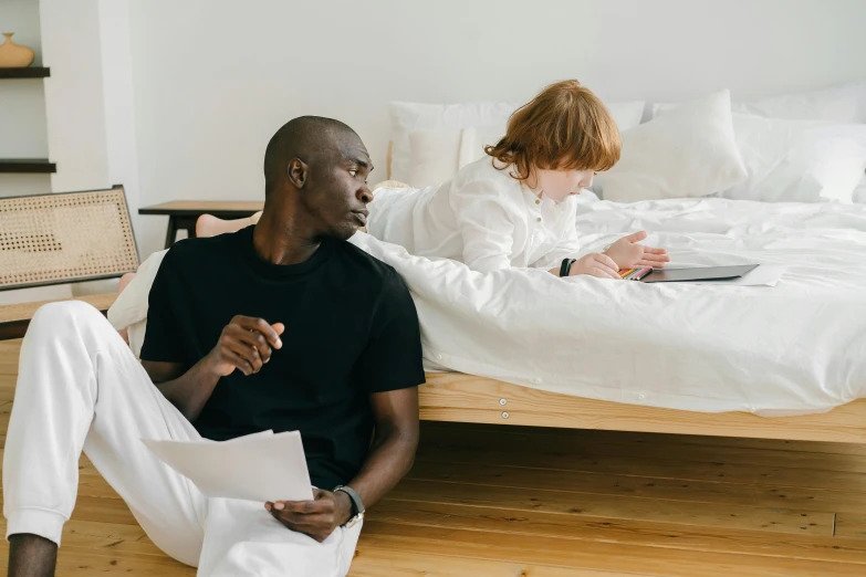 a woman sitting on the floor by a bed