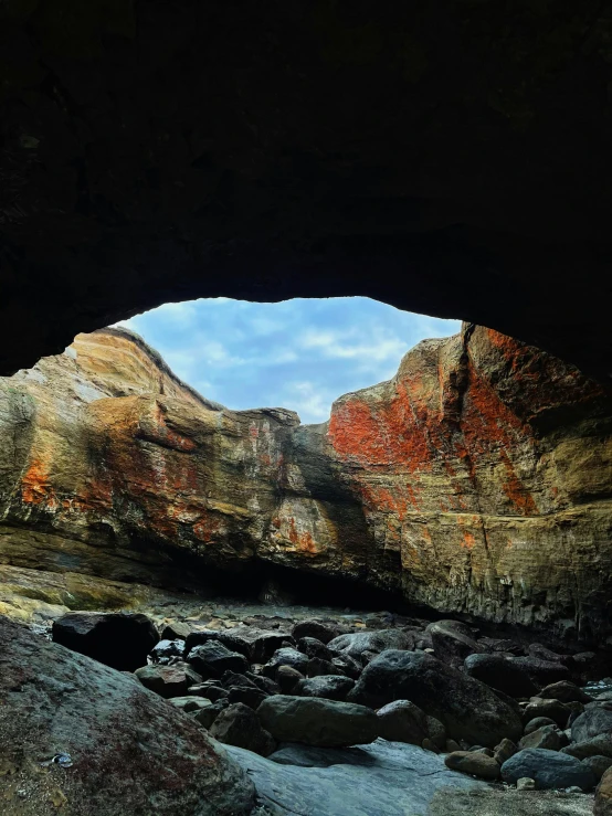 an empty cave near the shore where there is a mountain