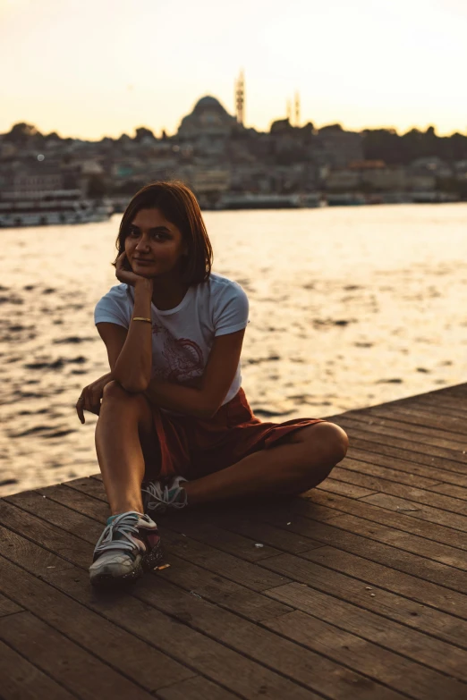 a woman sits on the pier looking at the water