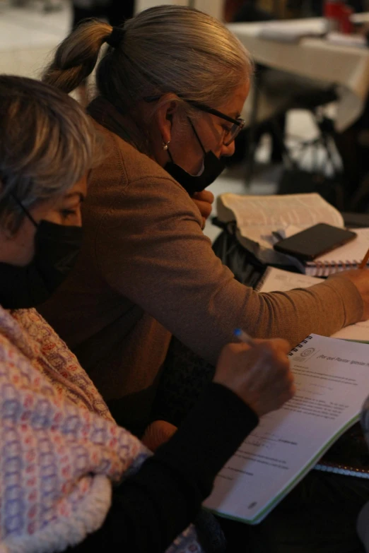 two women looking through paper and writing on notepads