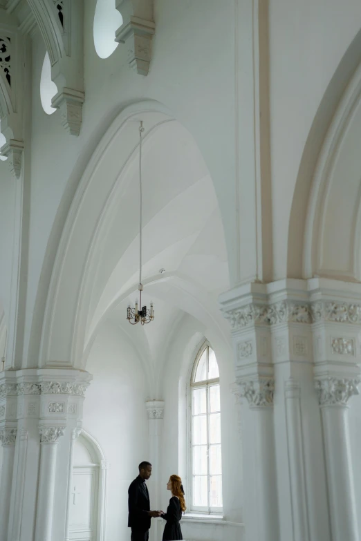 a man and woman are standing in a white building