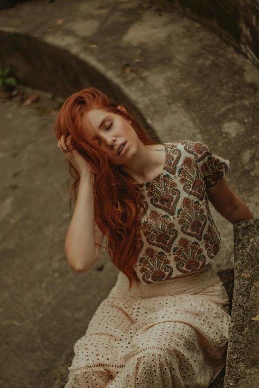 a red - haired woman rests on a rock