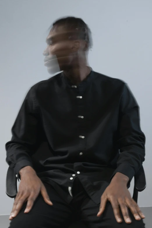 a man wearing black clothes and sitting down