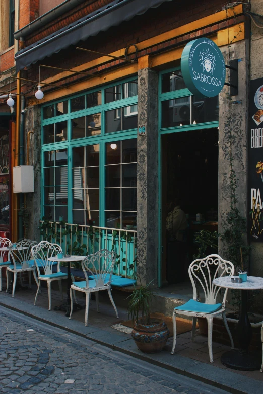 two white and teal chairs are outside a storefront