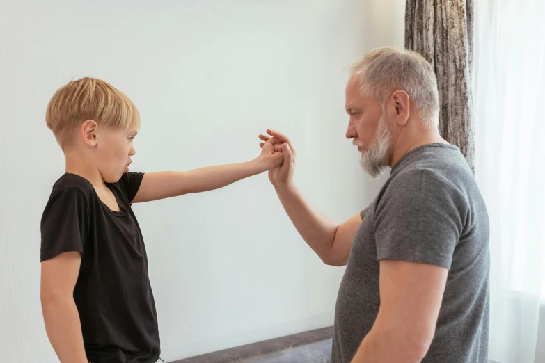 a boy is doing karate with an old man