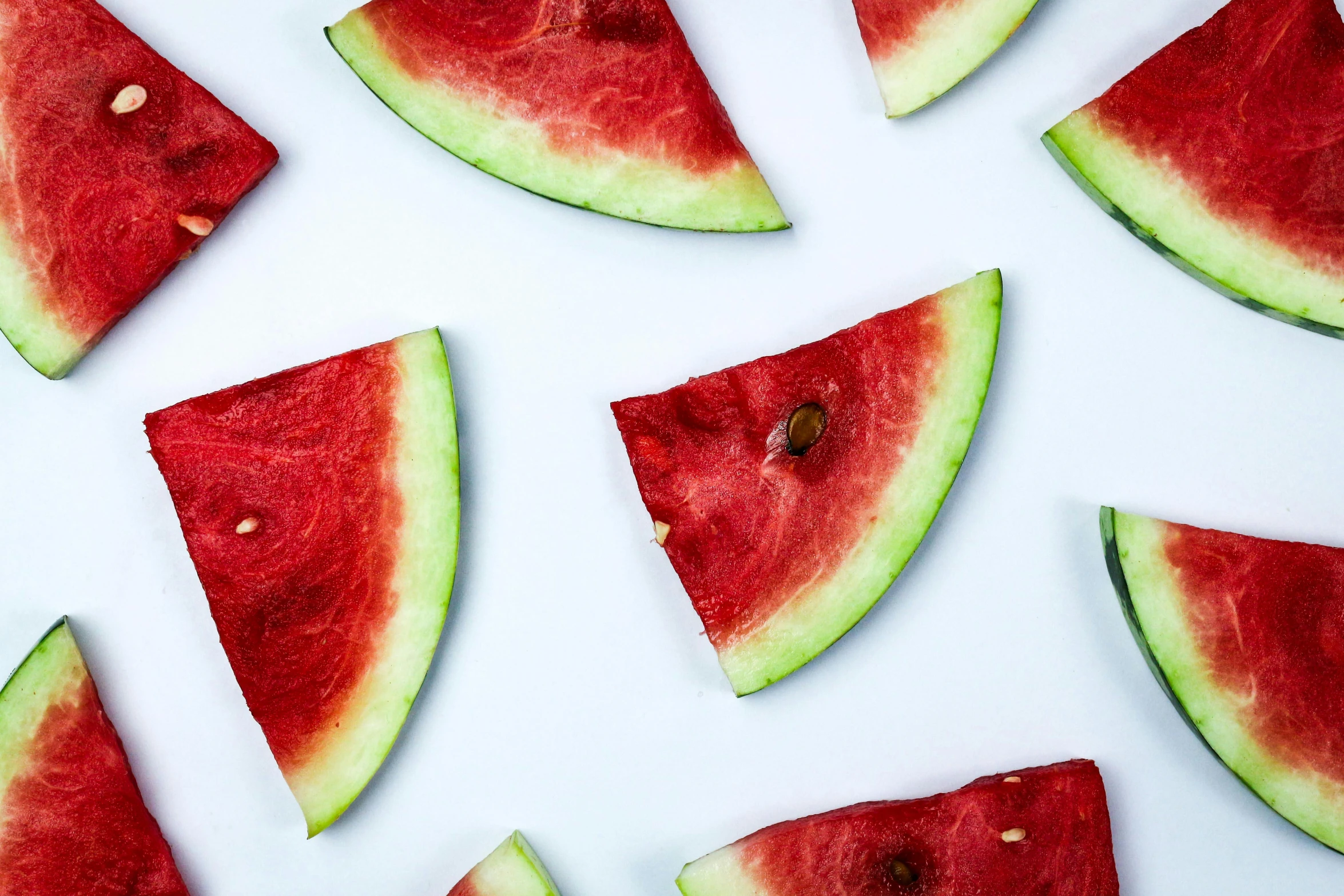 a number of slices of watermelon on a white table