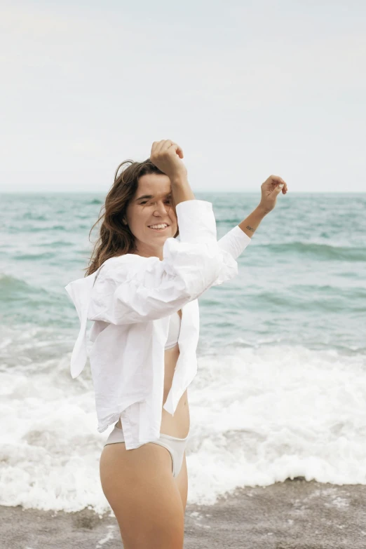 a woman on the beach with her arms in the air