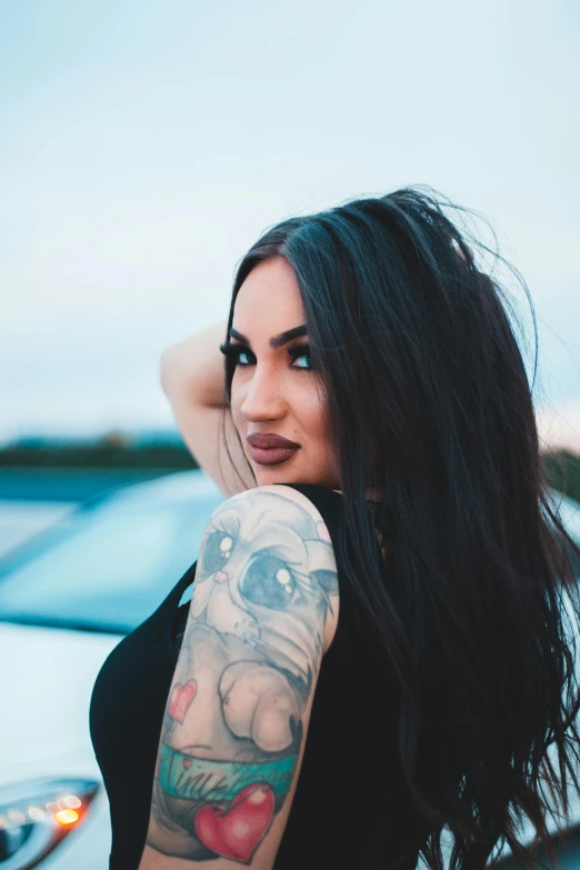 a woman with a cat tattoo sitting on the hood of a car