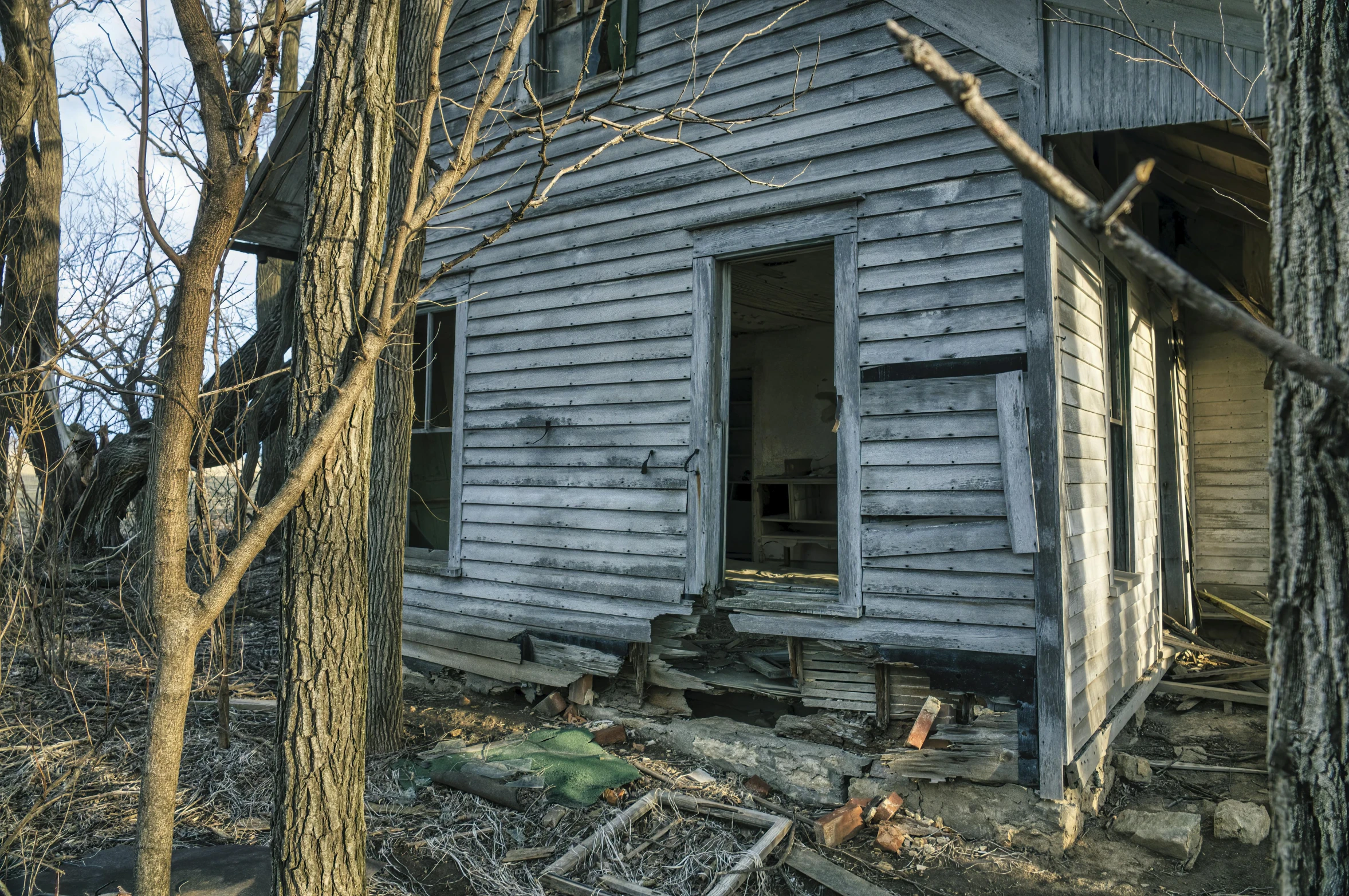 a old run down white house with trees around it