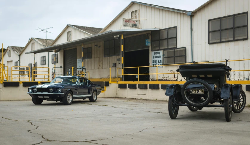 some classic cars sitting next to a white building