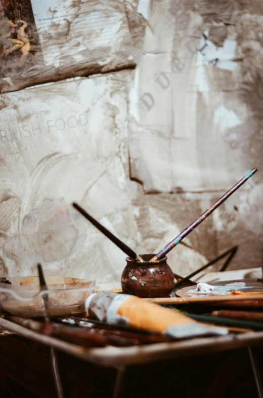 a wooden surface with some paint brushes and other paint supplies