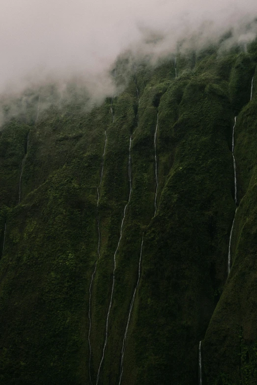 the clouds can be seen above an artificial waterfall in a green valley