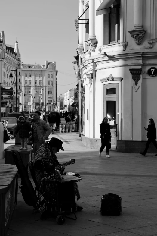 a person sitting down on a bench in front of some buildings