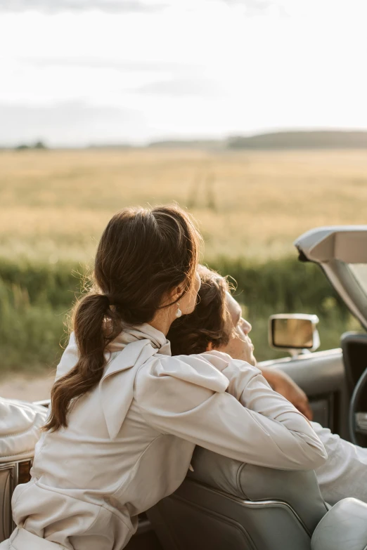 two women sitting in the driver's seat of a convertible car