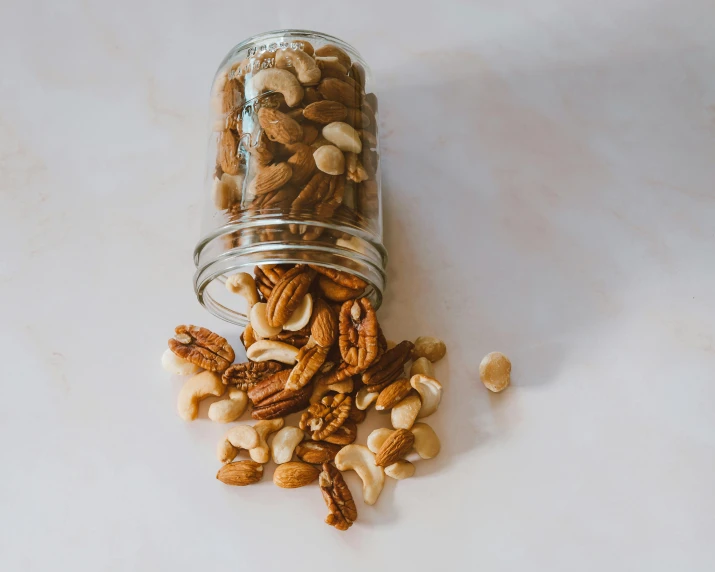 nuts sit in a glass jar atop a marble surface