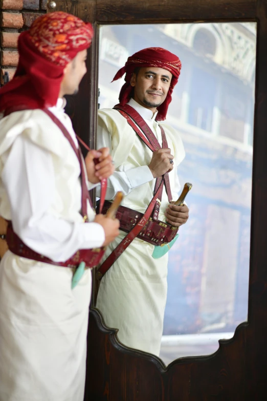 a man dressed in a traditional jordanian garb in front of a mirror