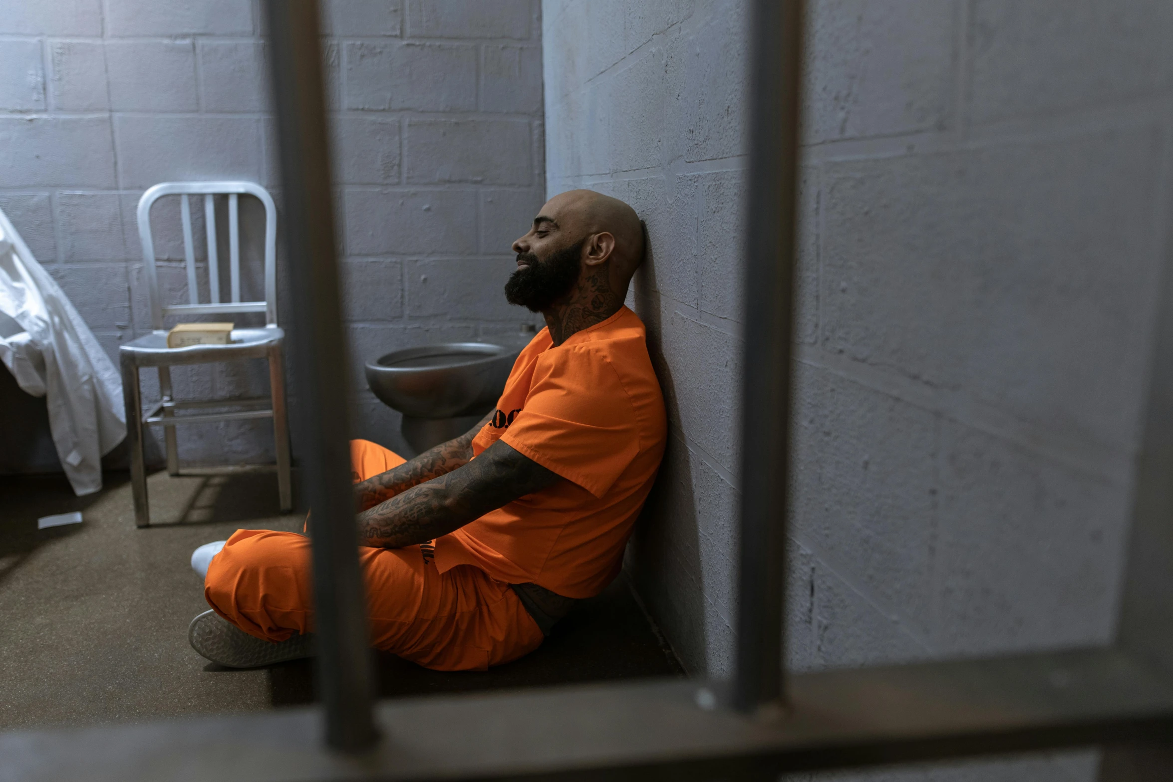 a bearded man sits down in an  cell