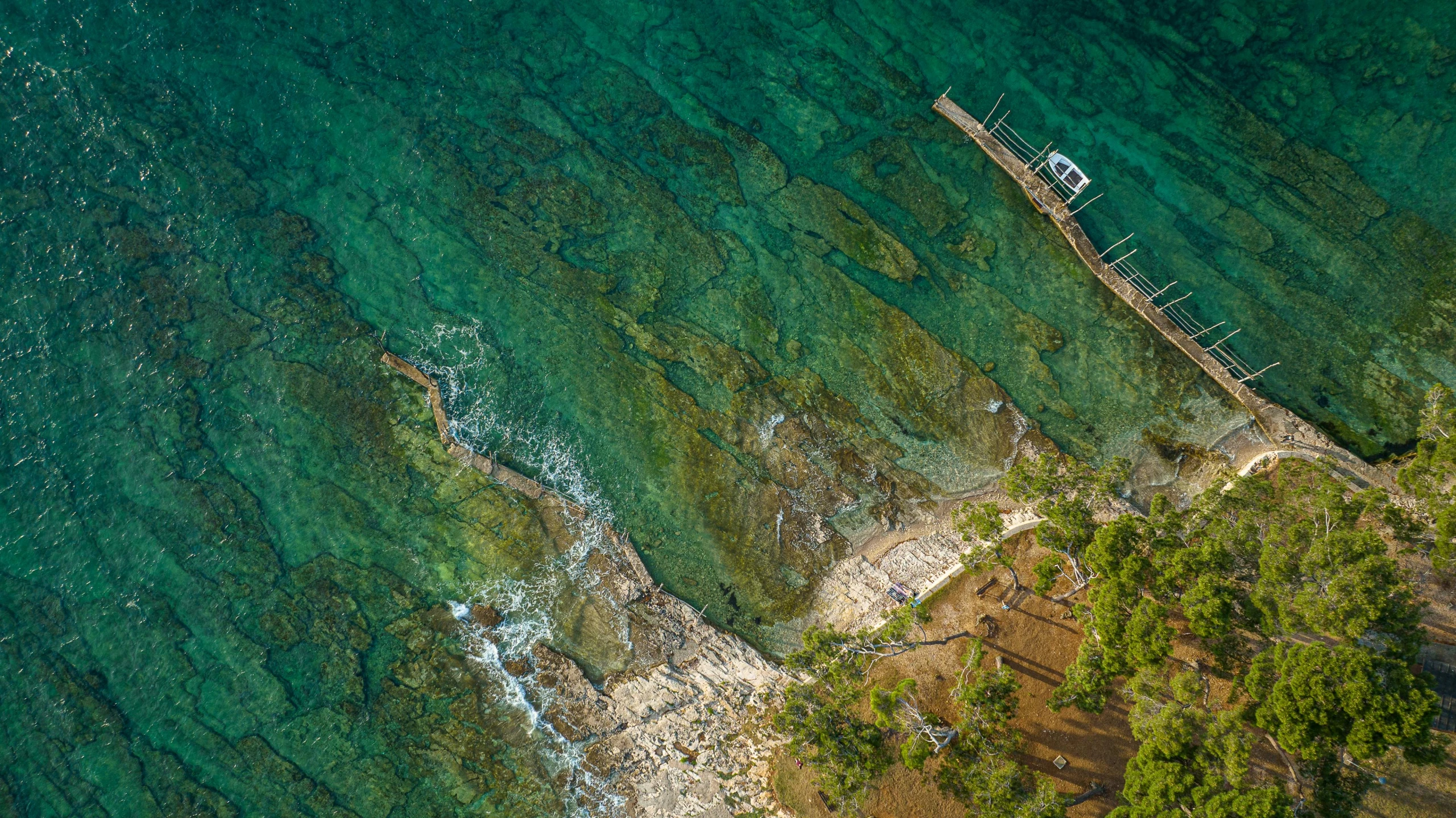 an aerial view of the coast with shallow turquoise water and sand