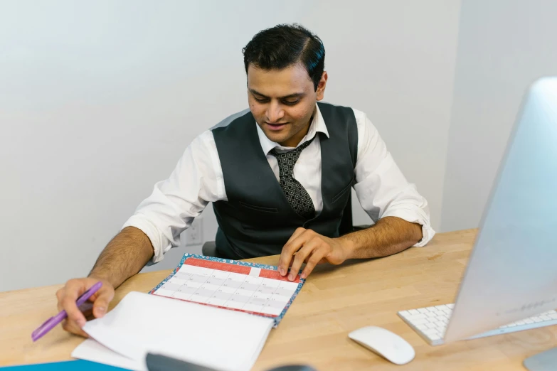 man in dress shirt sitting at desk with computer working